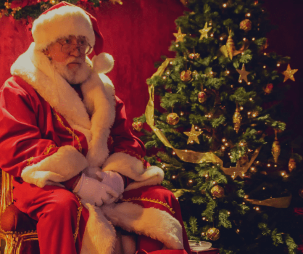 Als Weihnachtsmann verkleideter Mann neben einem Weihnachtsbaum